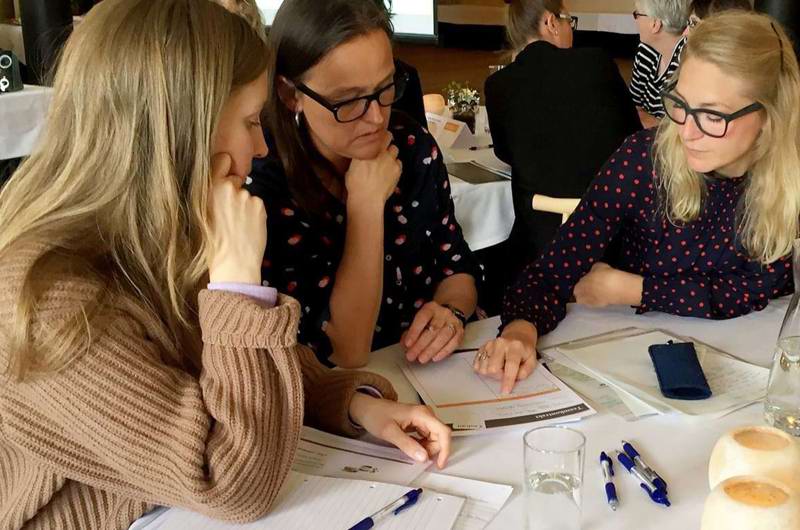 Medarbejdere er på kursus og sidder sammen og løser en opgave