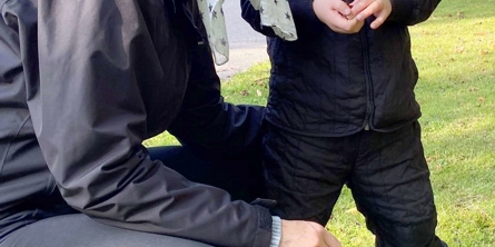 Forælder sidder på hug ved siden af barn