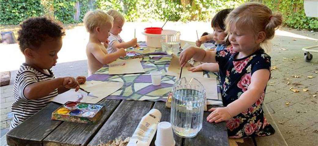 Børn maler ved bord på legepladsen